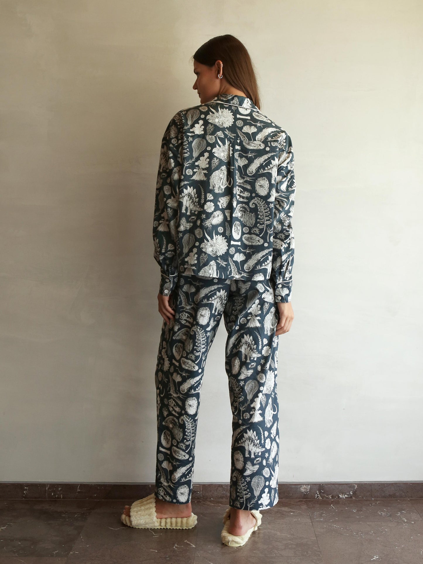 This high-quality womens Pj features the beautiful prehistoric dinosaurier illustrations by tattoo artist Suflanda. It coomes with boxy shaped long-sleeve shirt and long pants with Elasticated waist with drawstring.