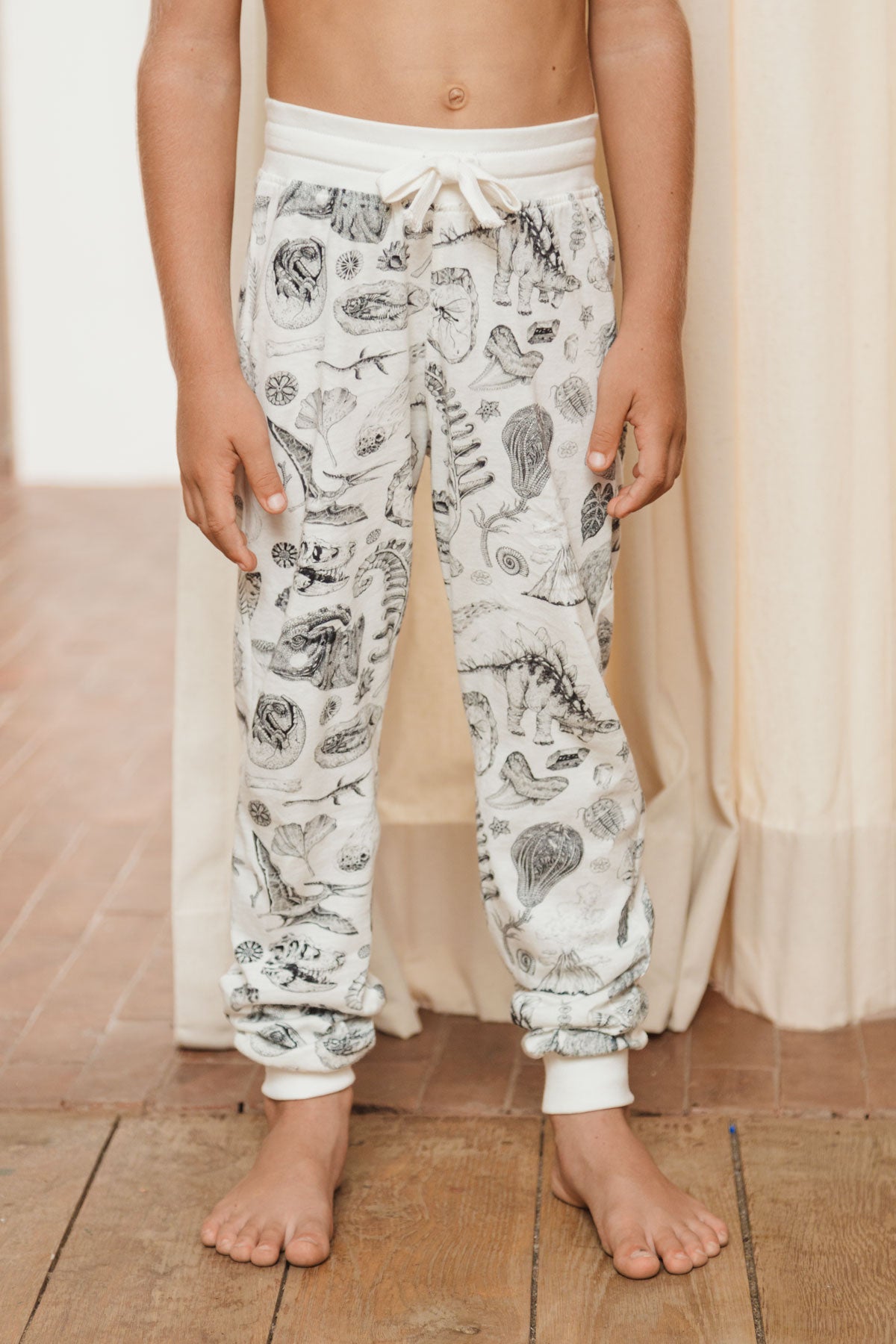 Load image into Gallery viewer, The lightweight jersey track pants made out of 100% cotton offer big comfort without compromising on cool. With our famous prehistoric print by Tattoo-Artist Suflanda the elasticated waist and the adjustable string detail will make sure you’re the coolest kid in town.
