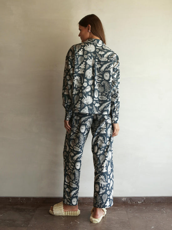 Laden Sie das Bild in den Galerie-Viewer, This high-quality womens Pj features the beautiful prehistoric dinosaurier illustrations by tattoo artist Suflanda. It coomes with boxy shaped long-sleeve shirt and long pants with Elasticated waist with drawstring.
